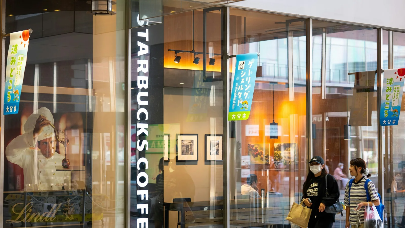 Entrada de una cafetería Starbucks con personas caminando frente a su fachada de vidrio